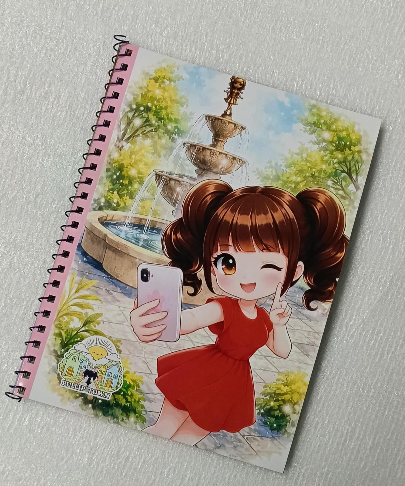Libreta Oficial de Pullip Town Barcelona 2026 Guarda tus ideas, bocetos, recuerdos y momentos especiales en la Libreta Oficial de Pullip Town Barcelona 2026, una pieza de merchandising elaborada artesanalmente para conmemorar una edición muy especial del evento. Cada libreta está realizada a mano, lo que la convierte en un recuerdo único para coleccionistas y amantes del universo Pullip. Su interior está compuesto por páginas de colores, ideales para escribir, dibujar, pegar fotografías o conservar autógrafos y recuerdos de tu visita al evento. Su práctico formato la hace perfecta para llevar contigo a convenciones, ferias o en tu día a día. Características Libreta oficial de Pullip Town Barcelona 2026. Elaborada completamente a mano. Páginas interiores de colores. Medidas: 20 × 15 cm. Producto de merchandising de edición especial. Información de entrega Este producto puede enviarse por correo. También puede recogerse en Pullip Town 2026 o en cualquiera de los eventos organizados por Dunia Eventos. Consulte los gastos de envío antes de realizar su pedido. Sobre el evento Pullip Town Barcelona 2026 se celebrará el 19 de septiembre de 2026 en el Hotel NH Collection Podium · Barcelona. Llévate un recuerdo artesanal de Pullip Town y conserva para siempre la magia de un evento pensado para todos los amantes de las muñecas Pullip